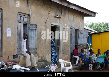 Un groupe d'adultes nigérians s'asseoir et se détendre dans l'après-midi à l'ombre d'une bâtisse Banque D'Images