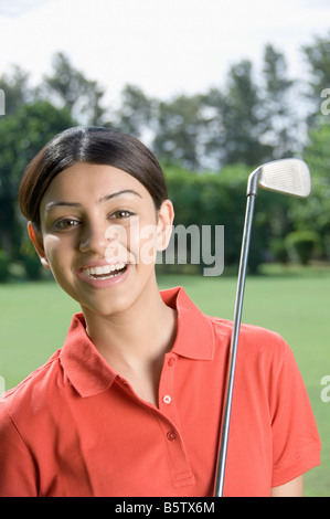 Femme avec un club de golf dans un terrain de golf Banque D'Images