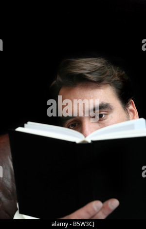 Concentré de l'homme lisant un livre avec le noir de l'espace en haut Banque D'Images