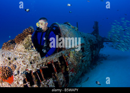 Diver dans le cockpit d'un avion chasseur Corsair WW II au large de l'Oahu, Hawaii. Banque D'Images