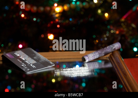 Lignes de cocaïne sur miroir simulé avec roulé de 20 livres sterling note en espèces carte de crédit platine avec arbre de Noël Banque D'Images