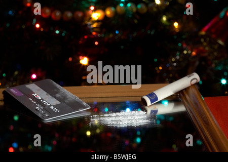 Lignes de cocaïne sur miroir simulé avec enroulé à 50 euros en espèces remarque avec carte de crédit platinum in front of Christmas Tree Banque D'Images