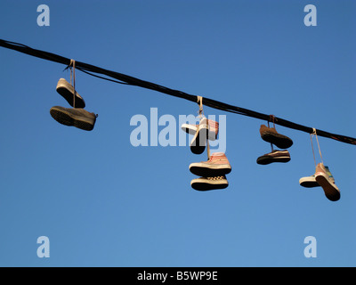 Paires de chaussures attachées ensemble et suspendues sur une ligne électrique Banque D'Images