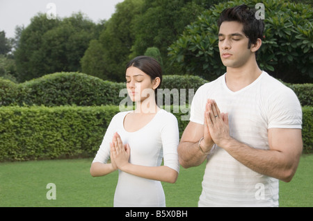 Couple practicing yoga in a park Banque D'Images