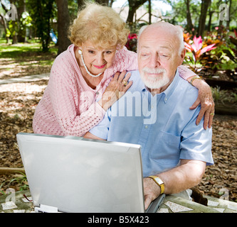 Senior couple bénéficie d'aide de leur ordinateur à l'extérieur Banque D'Images