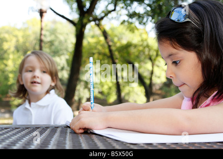 Une jeune fille a écrit son pratiques ABC s alors qu'un autre observe de loin Banque D'Images