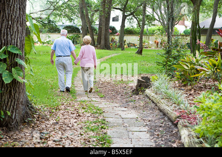 Senior couple flânant dans un jardin chemin ensemble une métaphore pour le voyage de la vie Banque D'Images