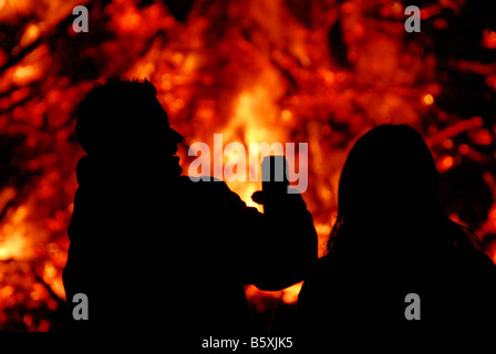 Silhouette de jeunes devant un feu de joie à Guy Fawkes nuit avec un verre dans la main Banque D'Images