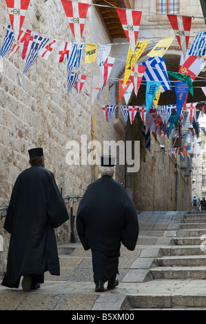 Vieille ville de Jérusalem Israël patriarcat grec orthodoxe deux prêtres marcher jusqu'à la rue sous les drapeaux Banque D'Images