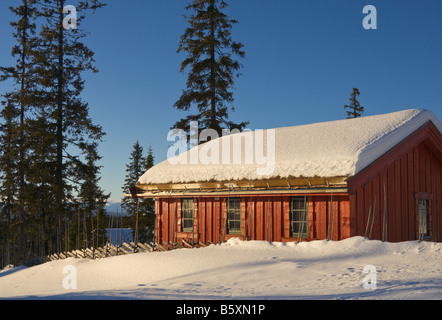 Chalet de vacances rouge dans paysage de neige à la tombée de la Norvège Valdres Banque D'Images