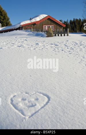 Chalet de vacances de neige et un smiley en forme de coeur dessiné dans la neige Norvège Valdres Banque D'Images