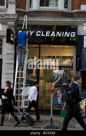 Nettoyage de l'entretien nettoyage à sec boutique avoir signer nettoyés dans le centre de Londres avec l'homme sur l'échelle Banque D'Images