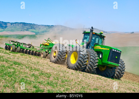 Un tracteur tire un semoir pneumatique à replanter le blé d'hiver endommagé par la neige au printemps dans la région de Washington Palouse Banque D'Images