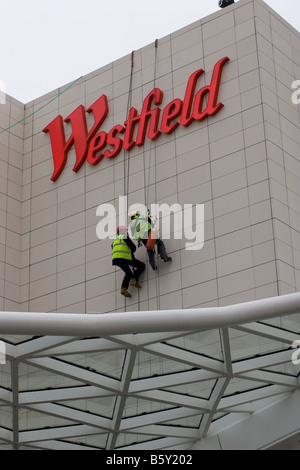 Le centre commercial de Westfield Shepherds Bush dans l'ouest de Londres abseilers les techniciens travaillant sur l'accès en cordée Westfield iconique sign Banque D'Images