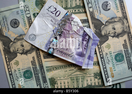 Livre Sterling endommagé sur un fond de US Dollars Banque D'Images