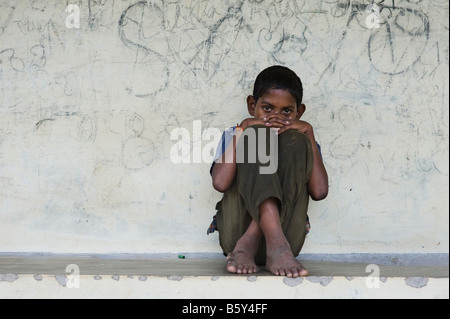 Triste jeune Indien assis contre un mur recouvert de graffitis Banque D'Images