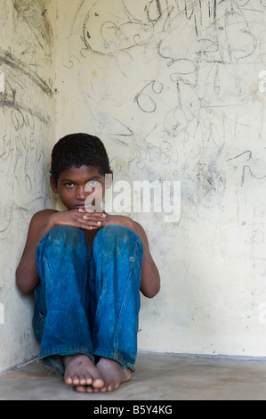 Triste jeune Indien assis contre un mur recouvert de graffitis Banque D'Images