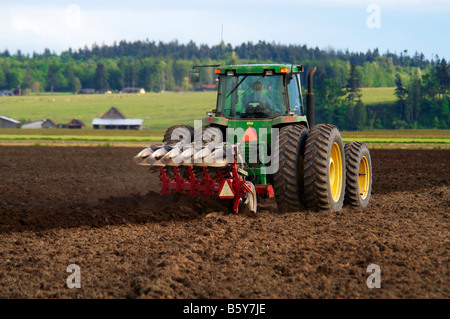 Un tracteur tirant une charrue de retournement commence la préparation du terrain pour préparer un lit de semence pour les pommes de terre au printemps Banque D'Images