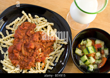 Un délicieux repas italien fait maison pâtes fraîches maison Gemelli avec sauce marinara avec une salade de tomates concombre Banque D'Images