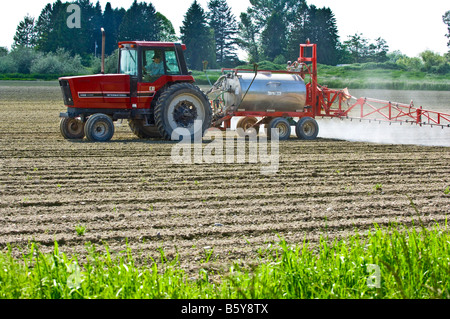 Un tracteur muni d'une plate-forme de pulvérisation pulvérise un champ de pommes de terre fraîchement plantés pour lutter contre les mauvaises herbes dans le nord-ouest de Washington Banque D'Images