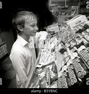 La petite enfance dans l'enfant UK sweet shop tenté par gamme de barres de chocolat Banque D'Images