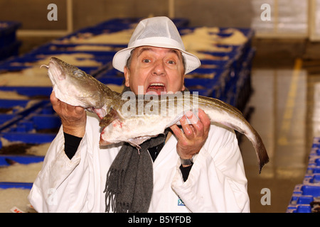 Grand cuisinier français Raymond Blanc tenant une morue à Peterhead marché de poisson de l'Aberdeenshire, Ecosse, Royaume-Uni Banque D'Images