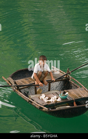 Garçon d'un village de pêcheurs flottant dans son petit bateau à rames Banque D'Images