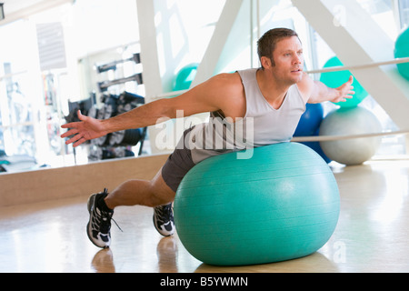 L'homme en équilibre sur ballon suisse At Gym Banque D'Images