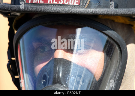 Un gros plan d'un pompier dans son masque respiratoire, casque et pignon Banque D'Images