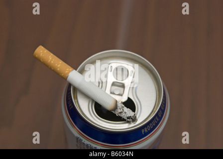 Cigarette sur une canette de bière utilisée comme cendrier Banque D'Images