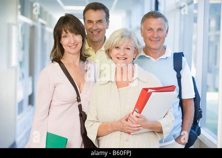 Quatre personnes debout dans le couloir avec des livres (high key) Banque D'Images