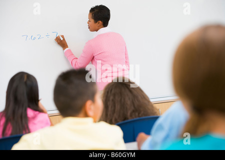 Les élèves en classe de mathématiques avec l'enseignant écrit sur l'avant (selective focus) Banque D'Images