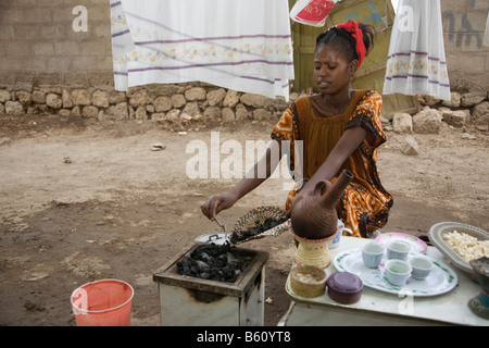 Jeune femme, 20-25 ans, d'effectuer une cérémonie du café en plein air avec des grains de café fraîchement torréfié avec de hauts de l'été Banque D'Images