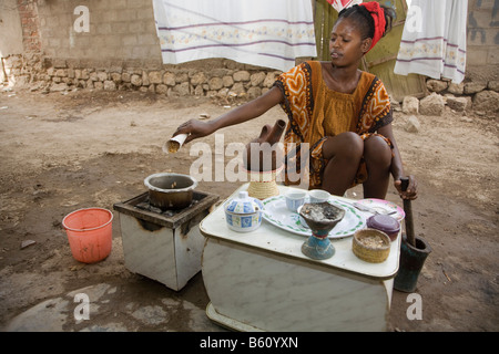 Jeune femme, 20-25 ans, d'effectuer une cérémonie du café en plein air avec des grains de café fraîchement torréfié avec de hauts de l'été Banque D'Images