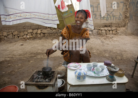 Jeune femme, 20-25 ans, d'effectuer une cérémonie du café en plein air avec des grains de café fraîchement torréfié avec de hauts de l'été Banque D'Images