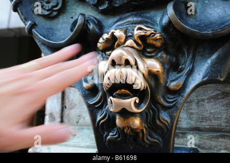 Atteindre la main pour toucher la tête en bronze d'un lion pour l'accomplissement d'un vœu, sur le bâtiment Residenz à Munich, Bavière Banque D'Images