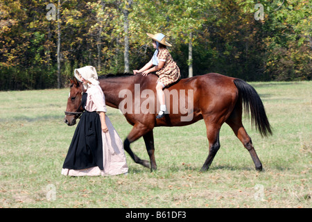 Une jeune fille bareback sur un cheval portant une robe prairie passage par une figure maternelle Banque D'Images