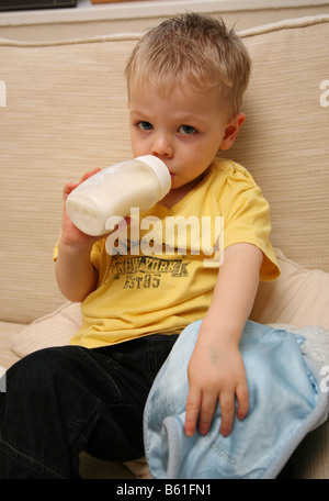 Fatigué 2 ans de boire du lait chaud à la bouteille et tenant son comfort blanket Banque D'Images