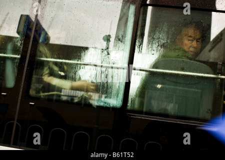 Un homme regarde par une fenêtre de l'autobus à Beijing en Chine en avril 2008 Banque D'Images