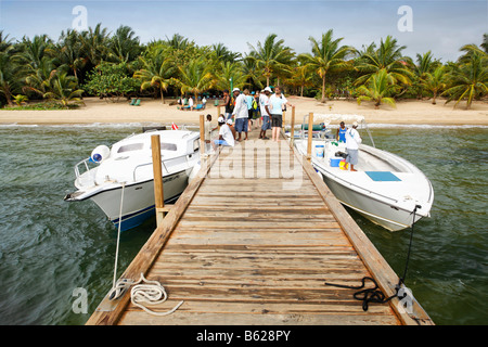 Quai avec les bateaux de plongée et les plongeurs en face d'une plage avec des palmiers, l'hôtel Hamanasi, Hopkins, Belize, Central, Dangria Banque D'Images