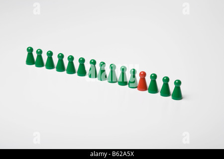 Pièces de jeu Vert debout dans une ligne d'une pièce de jeu rouge, symbolique d'être différent Banque D'Images