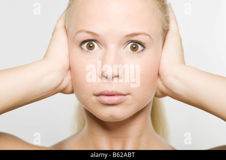 Jeune femme blonde couvrant ses oreilles Banque D'Images