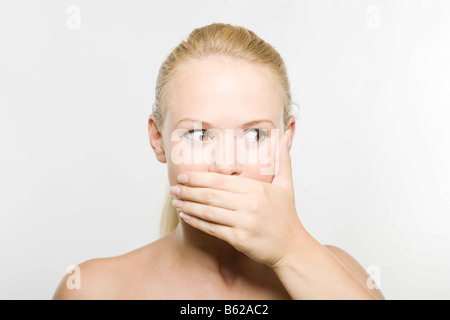 Jeune femme blonde couvrant sa bouche avec sa main Banque D'Images