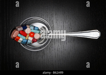 Cuillère de pilules sur un verre d'eau Banque D'Images