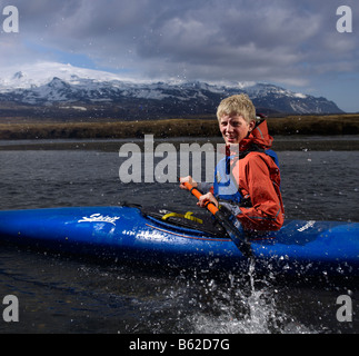 Teenage boy kayak en rivière avec Oraefajokull glacier dans l'arrière-plan, l'Est de l'Islande Banque D'Images