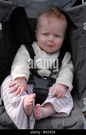 Bébé garçon attaché dans une poussette Banque D'Images