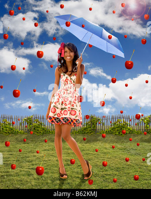 Jeune femme tenant un parapluie sous la chute des pommes Banque D'Images