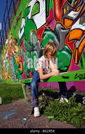 Dessin fille ou la copie de l'art du graffiti sur un mur peint à la bombe dans le cadre d'un projet communautaire d'égayer un parc local Banque D'Images