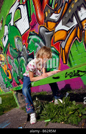 Dessin fille ou la copie de l'art du graffiti sur un mur peint à la bombe dans le cadre d'un projet communautaire d'égayer un parc local Banque D'Images