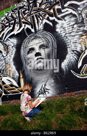 Dessin fille ou la copie de l'art du graffiti sur un mur peint à la bombe dans le cadre d'un projet communautaire d'égayer un parc local Banque D'Images